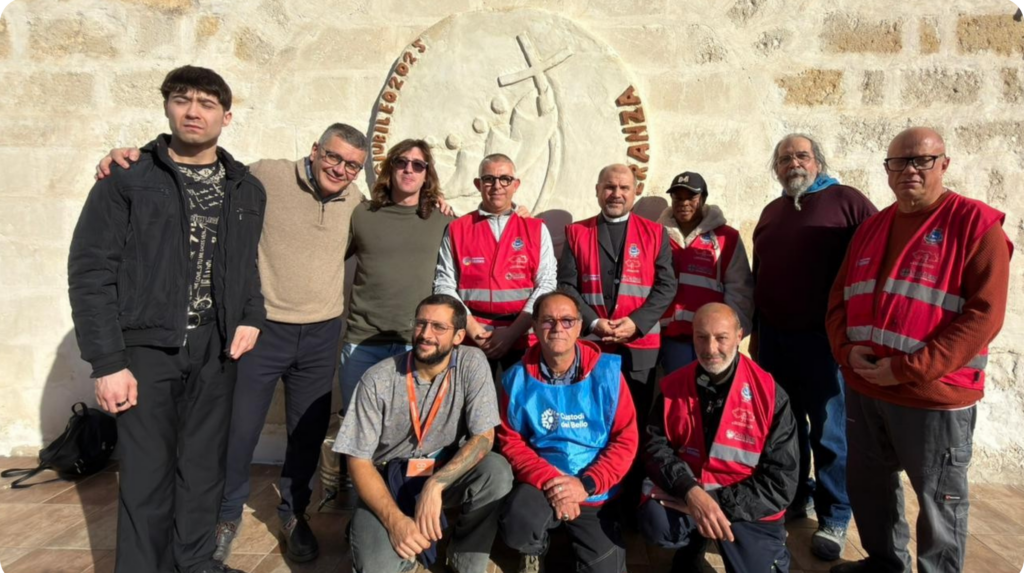 Un gruppo di persone di età diversa con i gilet del gruppo "Custodi del bello" davanti all'opera giubilare.